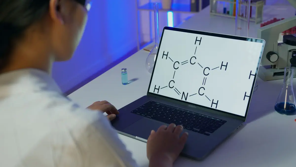 製薬会社の研究室で分子構造モデルを確認する研究者と、机上の試験管や培養皿（イメージ）