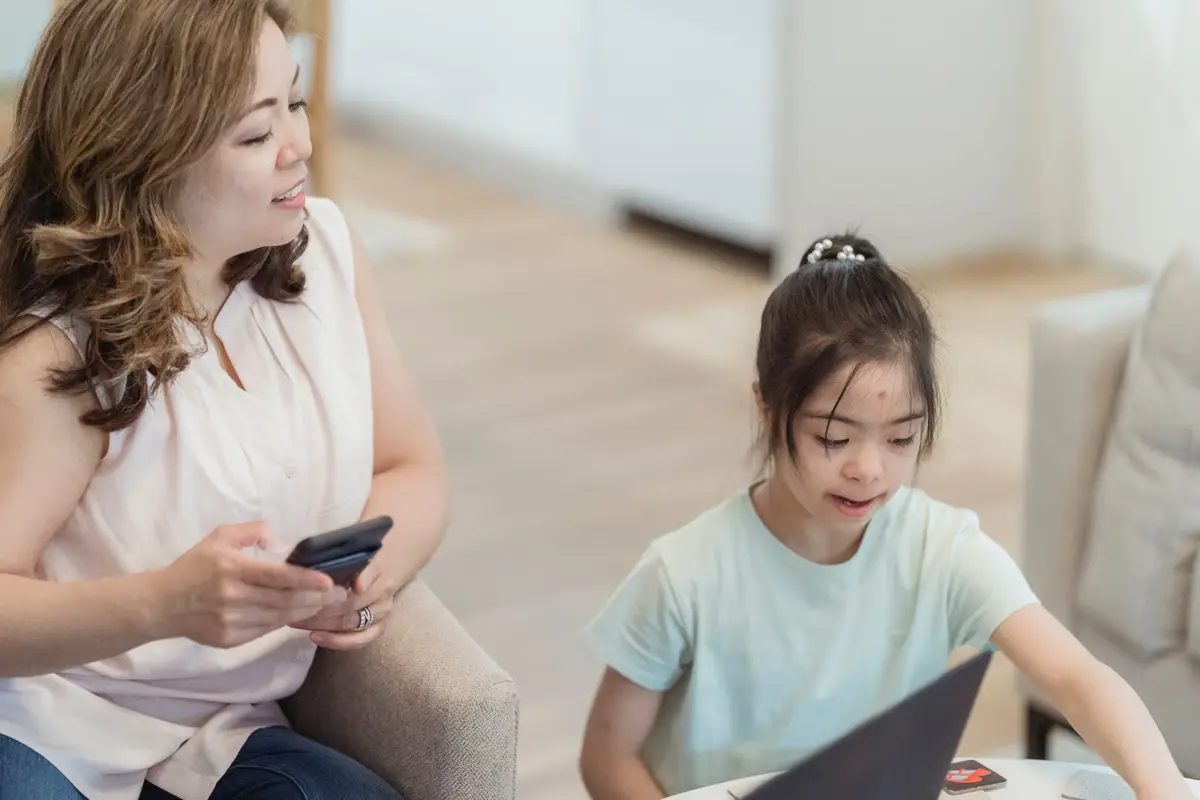 家長與孩子在家中查看手機上的 Apple 家人共享設定