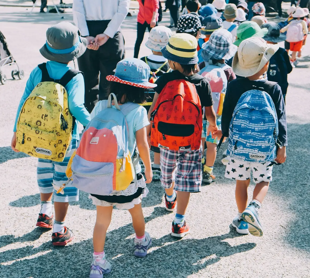 一群小學生揹著書包走向校園，象徵開學情境