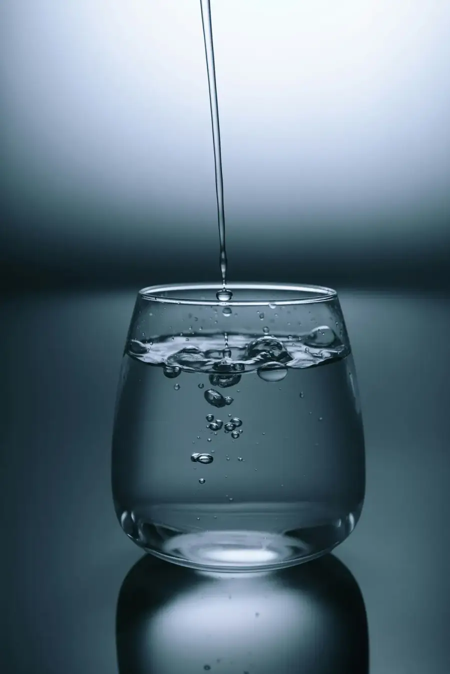 透明玻璃杯裝水，水花與光線交錯，示意每日飲水（示意圖）