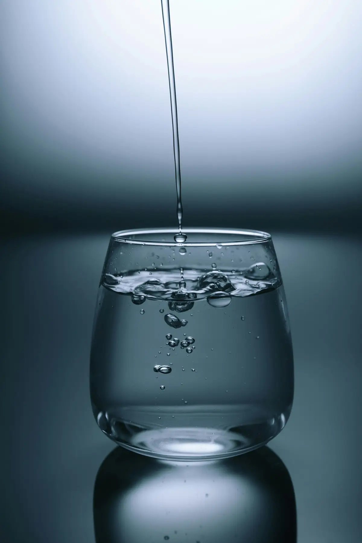 透明玻璃杯裝水，水花與光線交錯，示意每日飲水（示意圖）