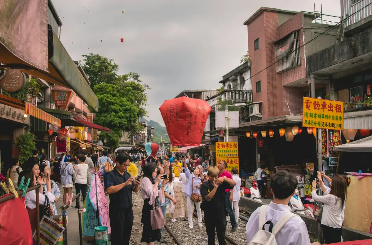 台灣廟會街道上的人潮與紙糊祭典物件，象徵民雄大士爺祭雨傘市集文化（示意圖）