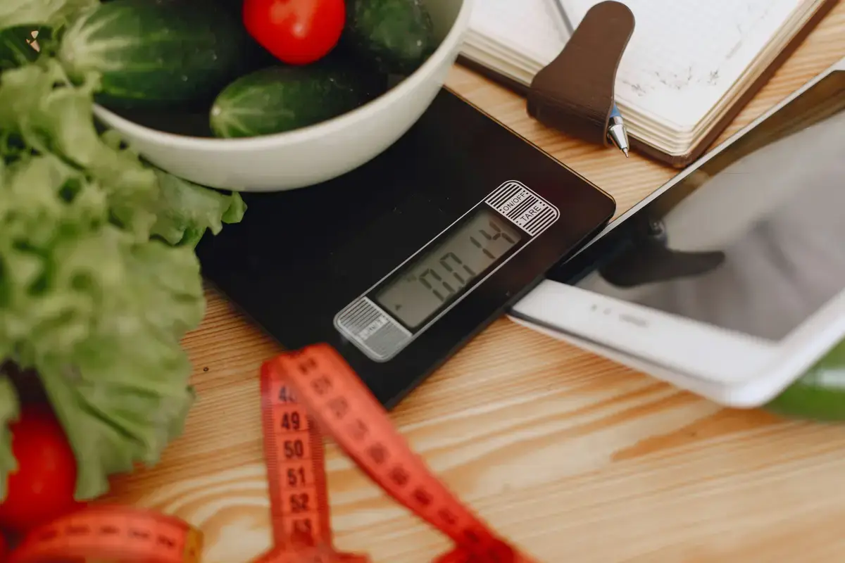 餐桌上有電子食物秤、量杯、健康餐盒與筆記，呈現計算減脂熱量赤字的情境