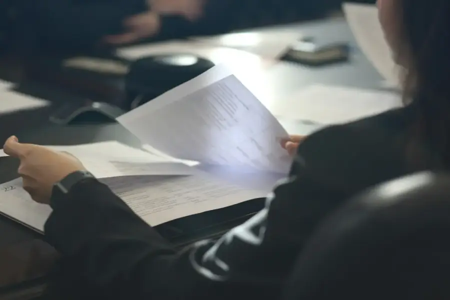銀行行員在櫃檯審視貸款申請文件，象徵金管會加強理財周轉金貸款查核
