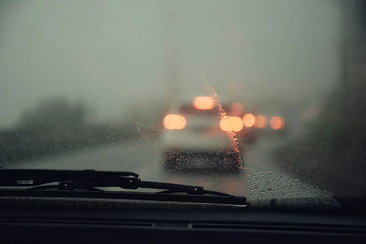 豪雨中的車流，前景可見擋風玻璃上的水滴與雨刷