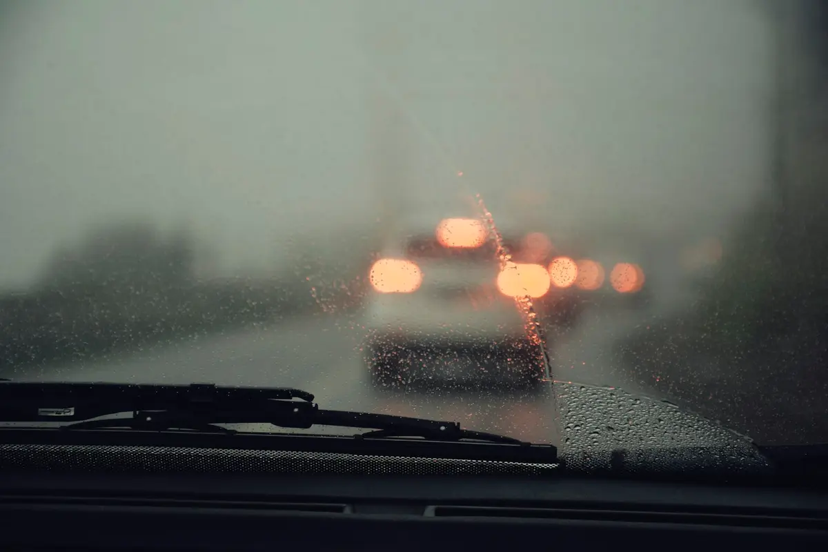 豪雨中的車流，前景可見擋風玻璃上的水滴與雨刷