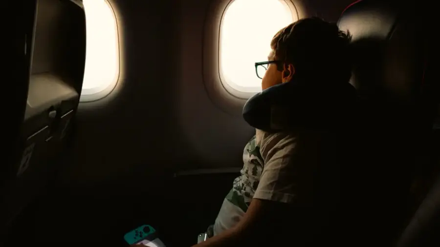 兒童坐在飛機靠窗座位，望向窗外的機翼與天空