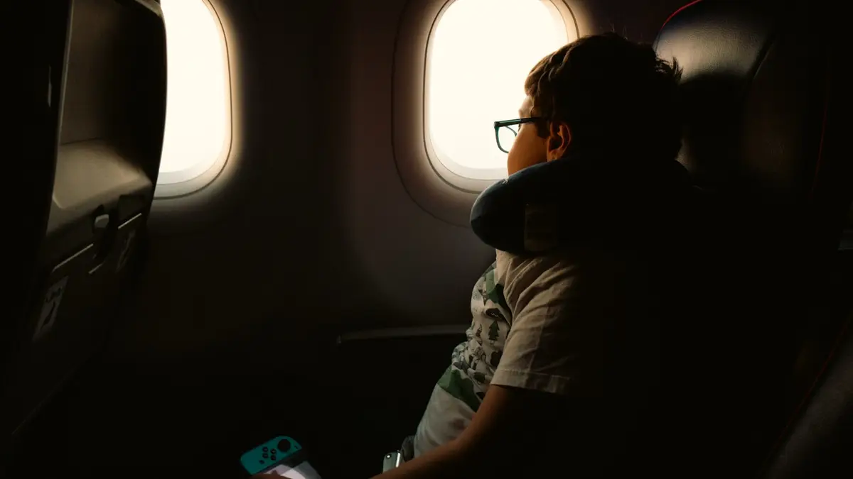 兒童坐在飛機靠窗座位，望向窗外的機翼與天空