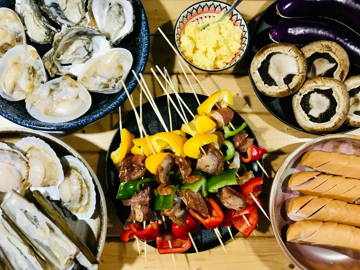 戶外餐桌旁的烤肉爐與烤肉串，呈現中秋烤肉聚餐情境