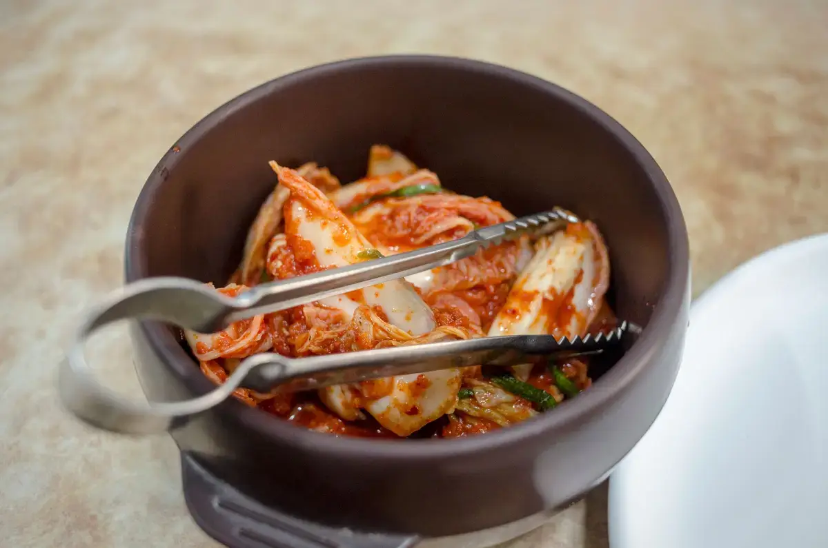 玻璃罐泡菜、白菜與廚房桌面，呈現泡菜製作與飲食文化的示意畫面
