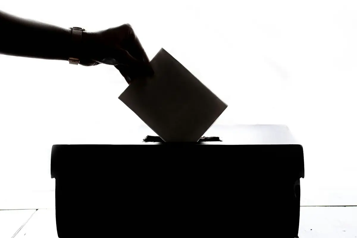 A ballot box beside paper ballots on a table (illustrative image)