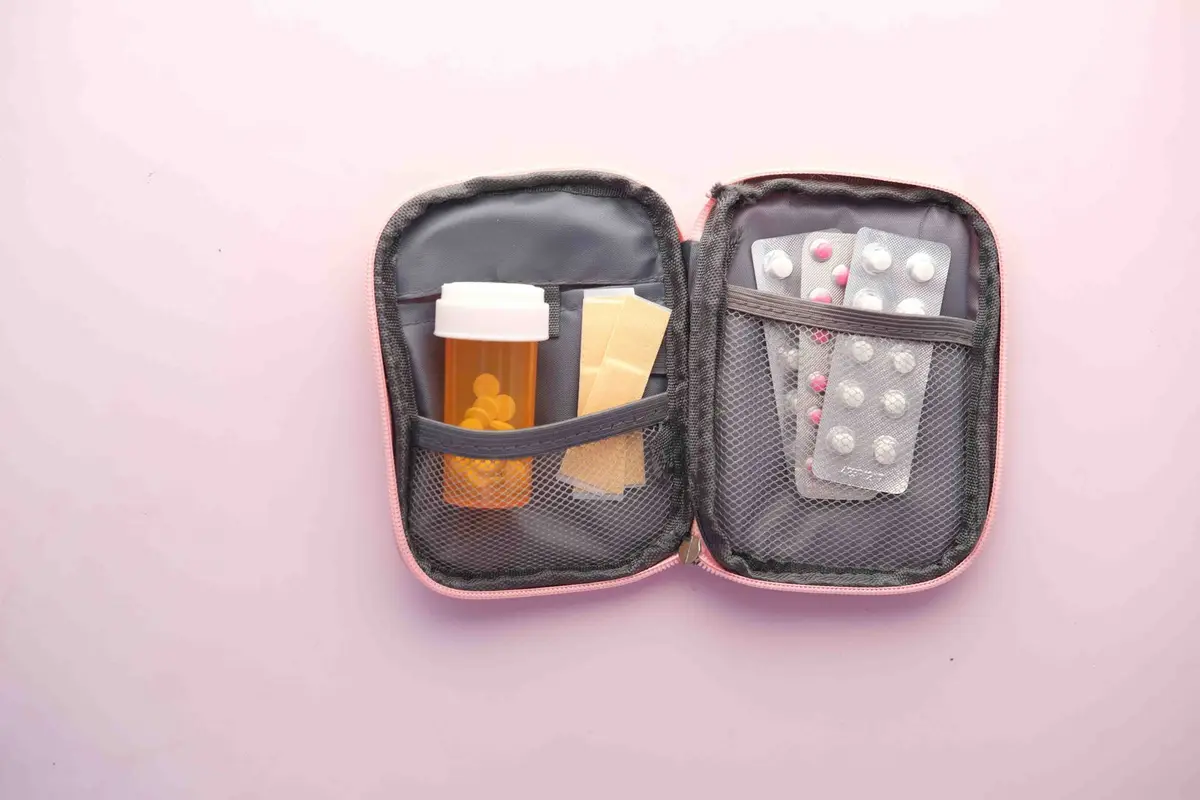狗狗與貓咪在家中藥品櫃旁被飼主看顧，桌上有無品牌識別的藥錠與藥盒，飼主拿手機準備聯絡動物醫院