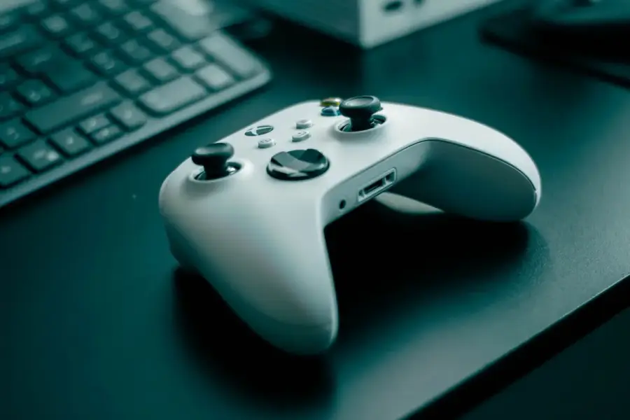深色桌面上的白色遊戲控制器與遊戲主機，呈現數位遊戲使用情境