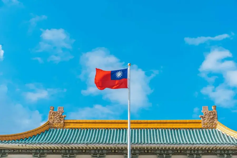 台灣傳統建築屋頂上飄揚的中華民國國旗，藍天白雲為背景（示意圖）