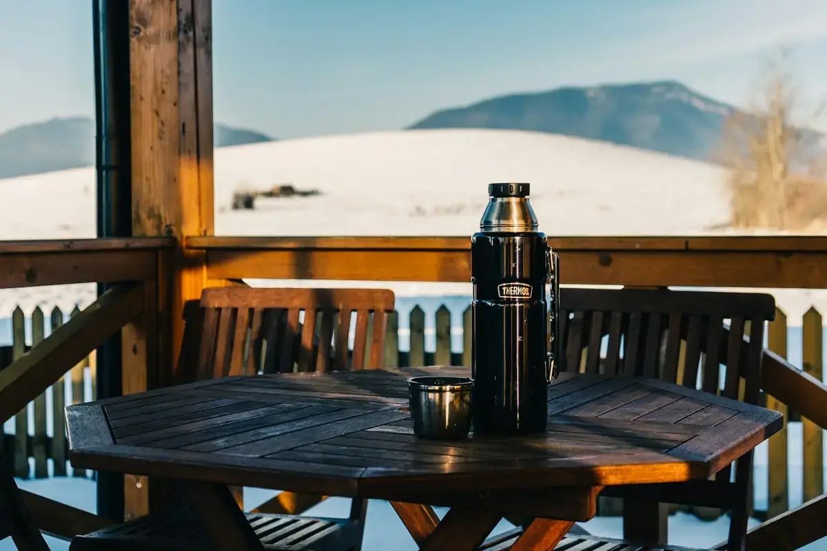 雪地窗邊木桌上的不鏽鋼 Thermos 保溫瓶