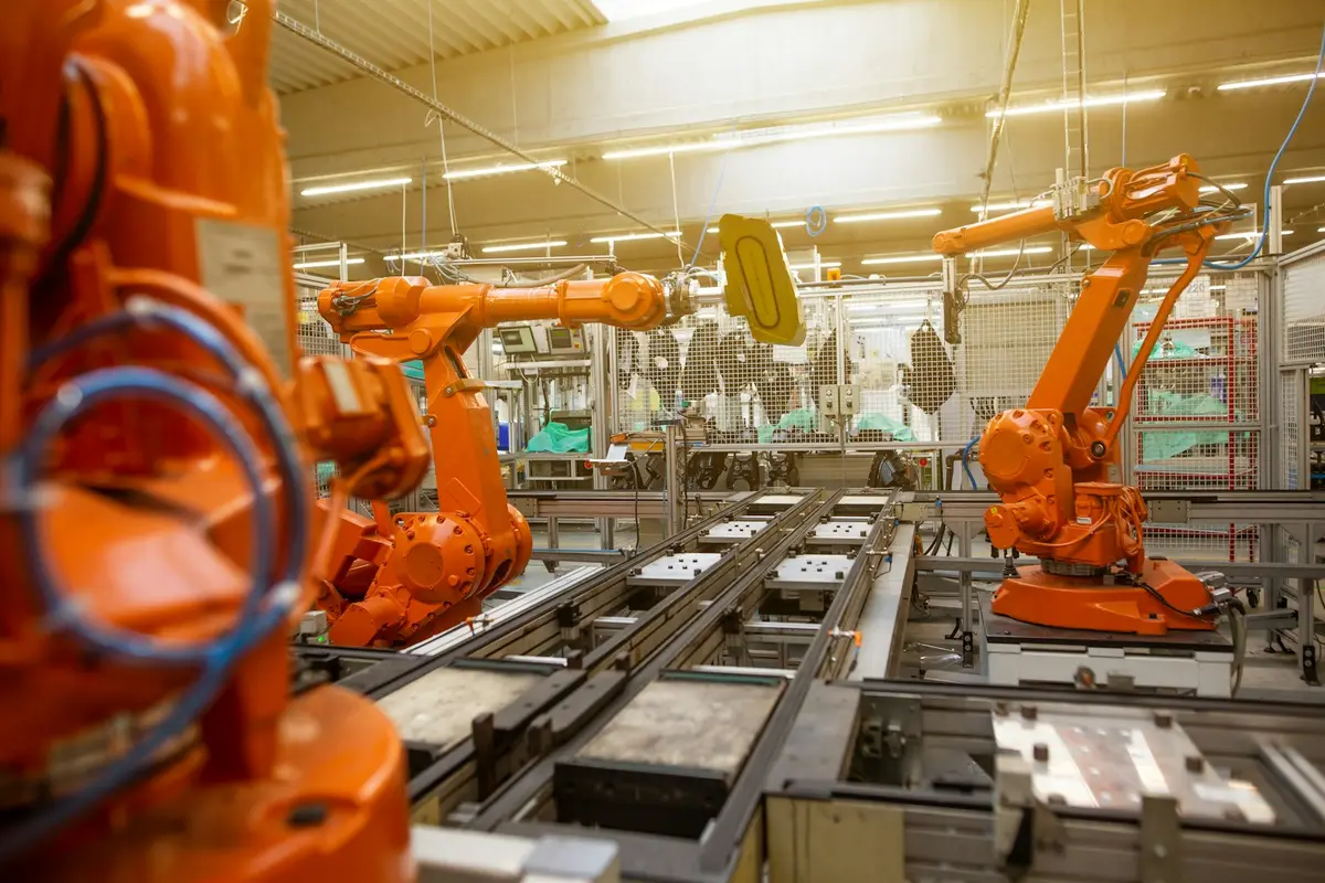 工廠內橘色工業機器手臂運作示意圖，象徵機器人科技（示意圖）