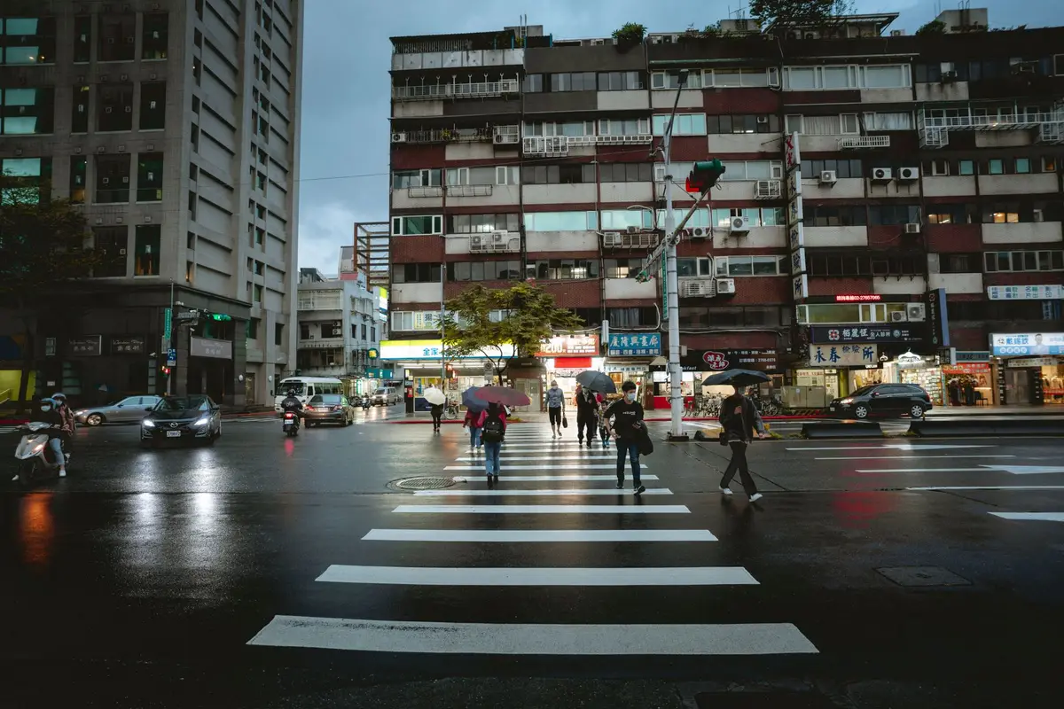 雨天台灣市區路口與行人，呈現颱風豪雨期間查詢停班停課公告的情境