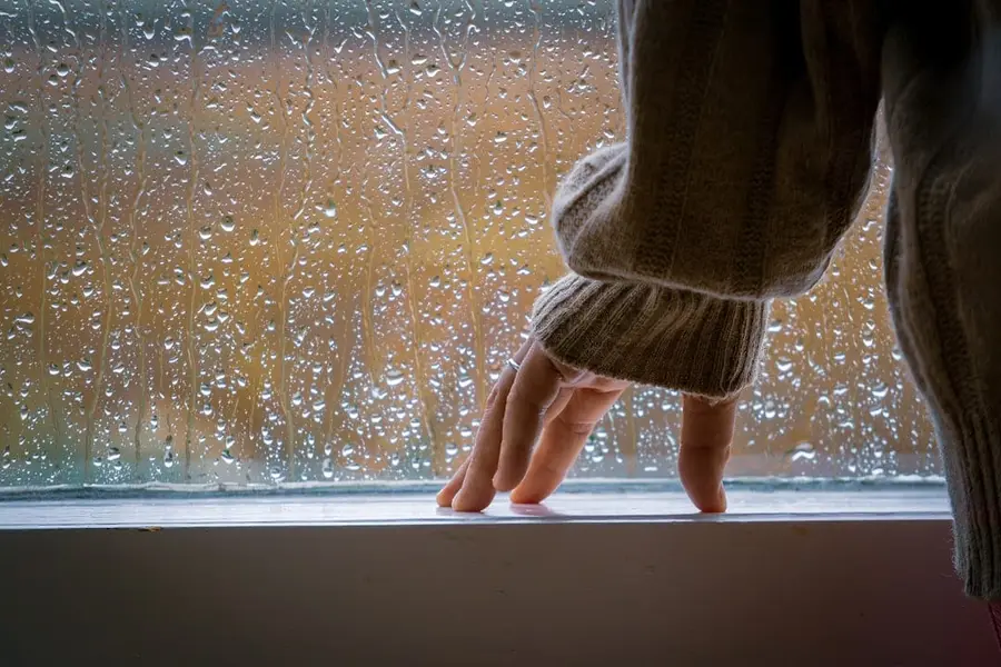 陰雨天中年長者手扶膝蓋，象徵退化性膝關節炎與天氣對關節疼痛的影響