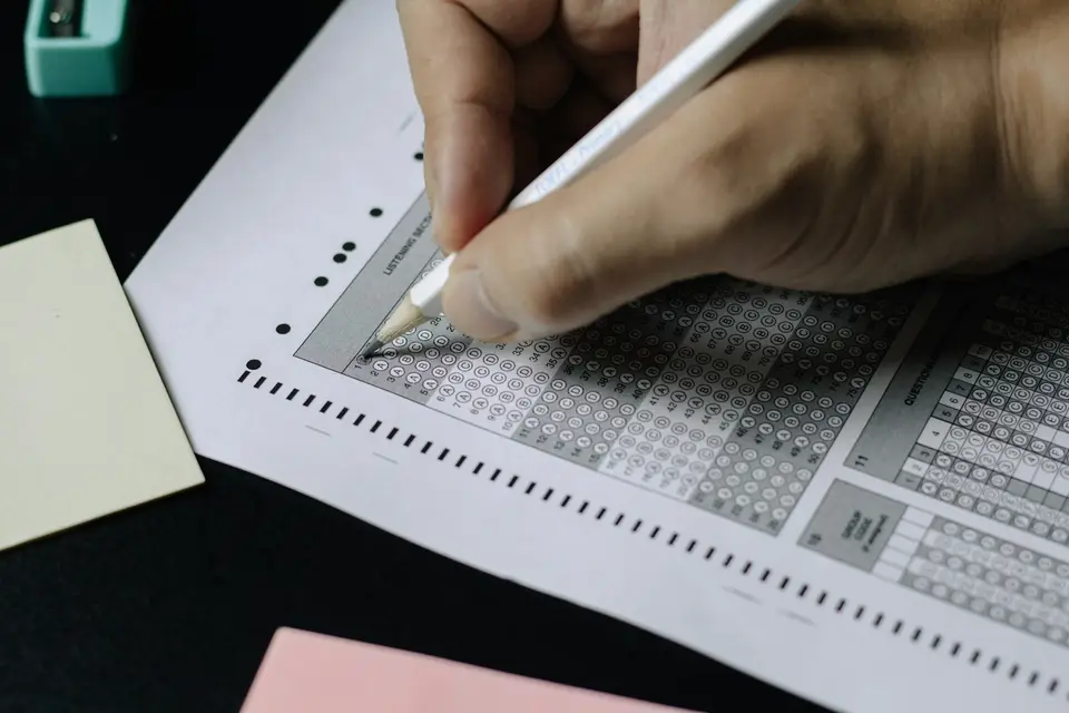 書桌上擺著一張填答用的選擇題答案卡與一支鉛筆，象徵猜題情境（示意圖）
