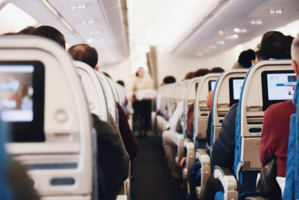客機客艙走道與座位區，呈現機組員提供服務的工作場景