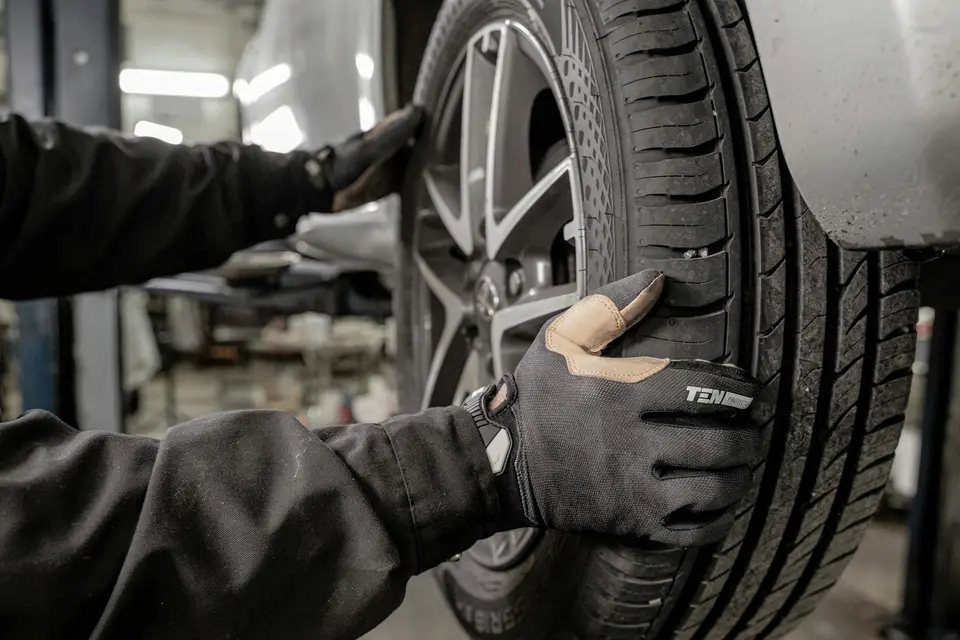 汽車技師在保養廠蹲下檢查輪胎胎紋狀況