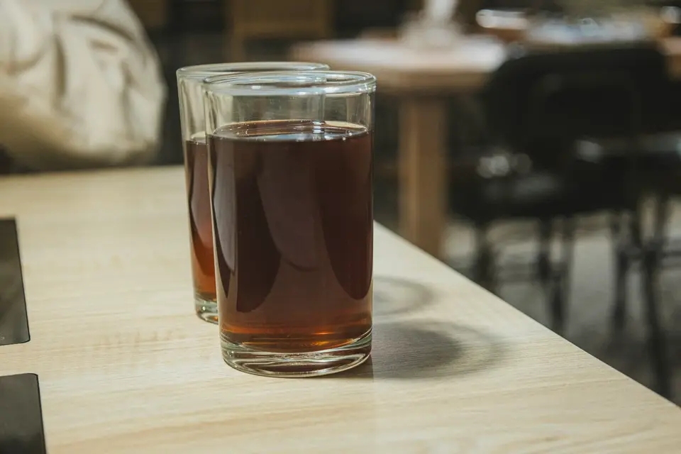 搖好後倒入玻璃杯 將冰紅茶從調飲器倒入玻璃杯的飲料桌面場景,呈現泡沫紅茶的飲用方式