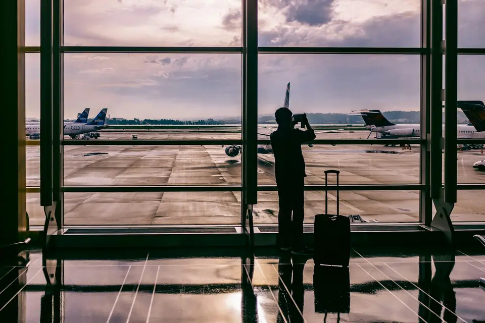 旅客在機場拖著行李查看手機上的航班與行程資訊