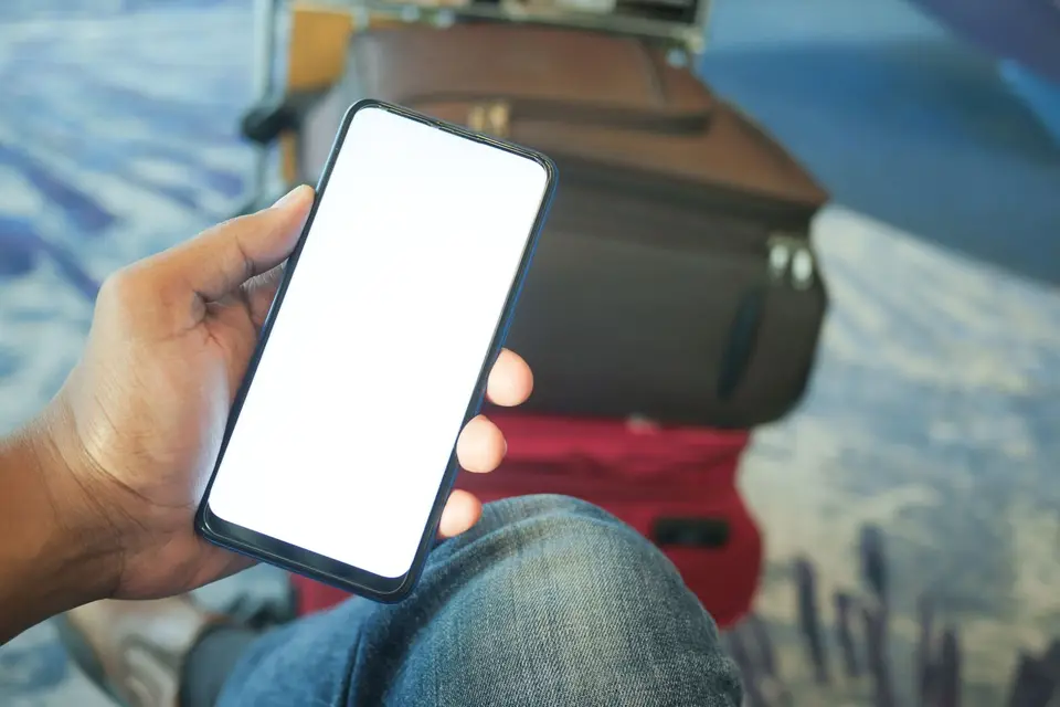 旅客在候機區低頭查看手機上的旅遊資訊（示意圖）