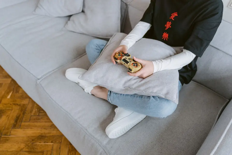 沙發上的玩家拿著遊戲控制器，呈現家庭成員使用個別帳戶遊玩遊戲的情境