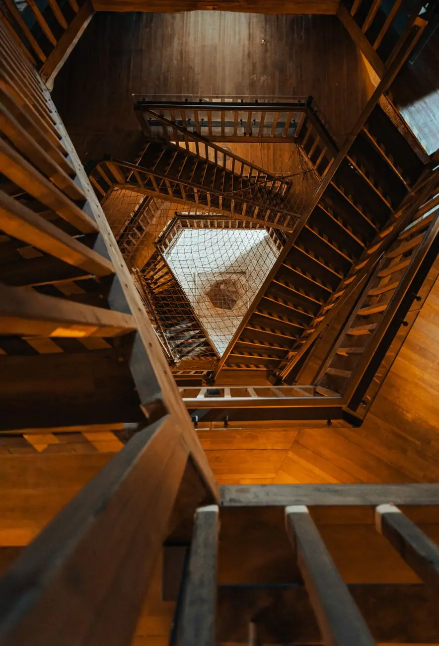 木造建築內的多層樓梯向上延伸，象徵不同方案層級與席次規模