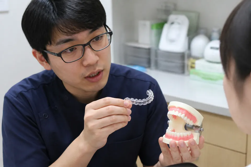 牙醫師手持透明維持器與矯正牙齒的石膏模型