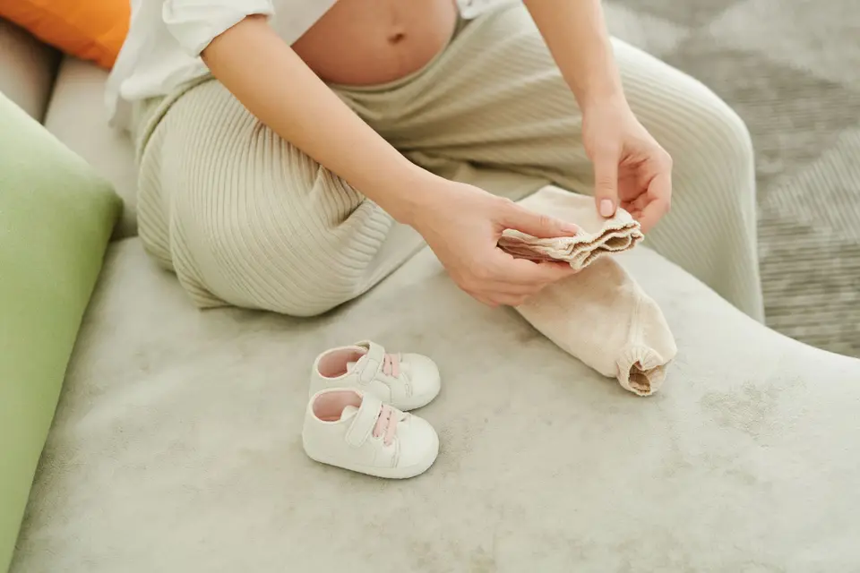 孕婦整理嬰兒衣物與小鞋的示意畫面