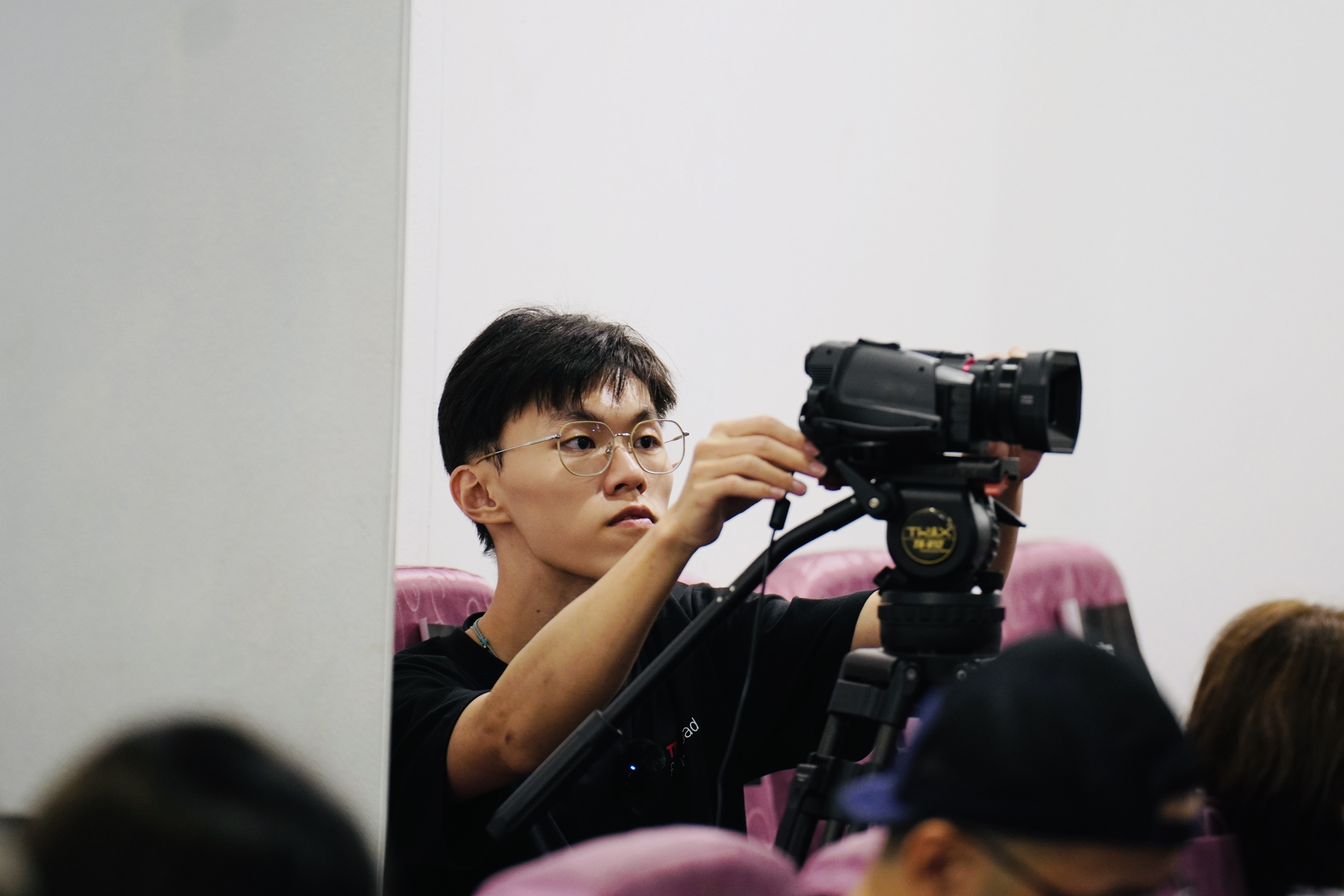 TEDxRenaiRoad志工在觀眾席使用攝影機記錄活動，呈現影像工作也是舞台的一部分