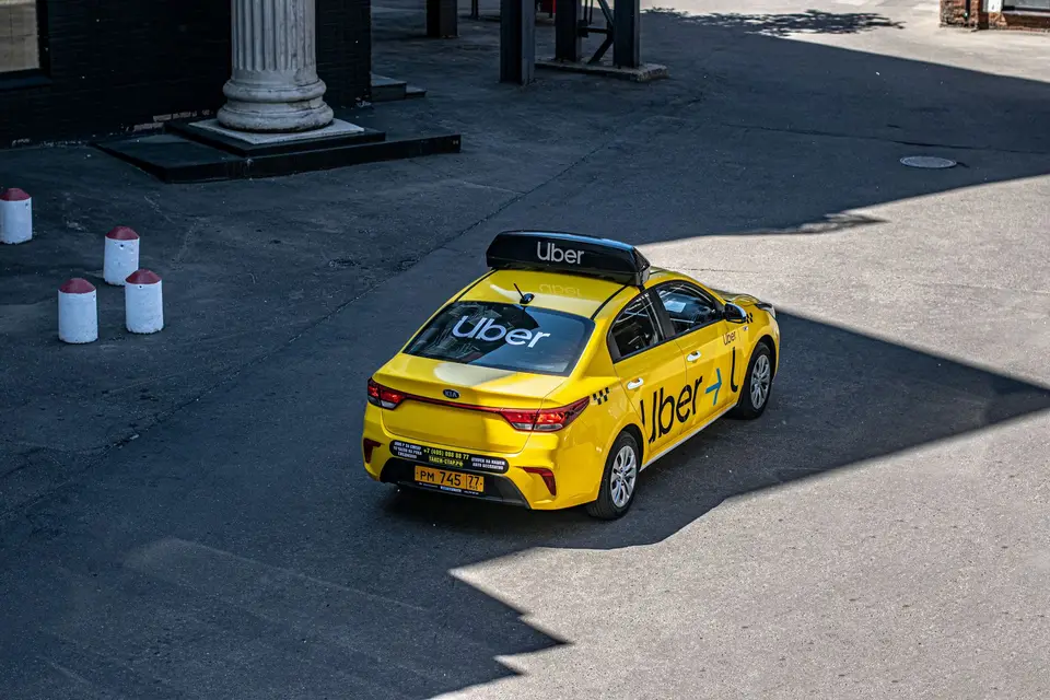 黃色 Uber 計程車停在城市道路旁，呈現自動駕駛載客服務的應用場景