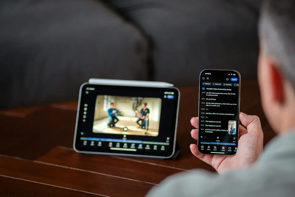男士手持 iPhone 操作影片剪輯 App，背景 iPad 顯示正在剪輯的影片畫面